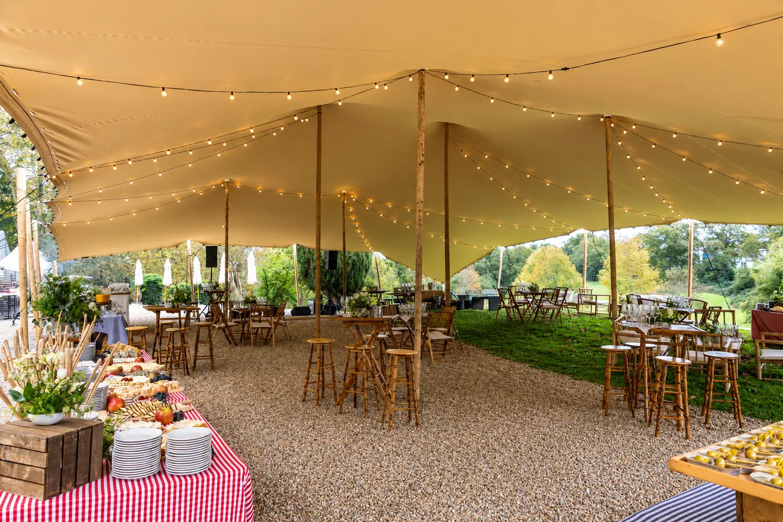 Mesas altas y buffet bajo una carpa abierta al exterior