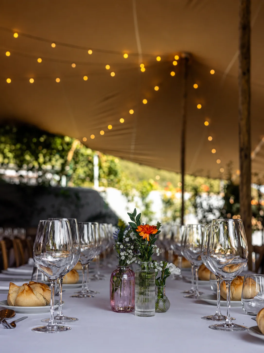 Mesa con flores y copas bajo una carpa con guirnaldas